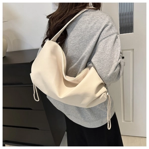 Detail of soft cream white nylon shoulder bag with drawstring accents and zipper closure