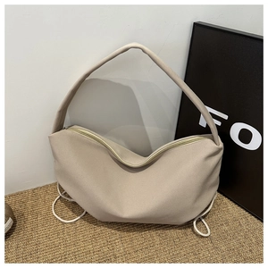 Detail of beige nylon crescent hobo bag with side drawstring accents and zipper top