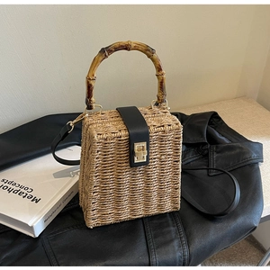 Detail of woven straw handbag featuring premium bamboo handle and leather buckle strap