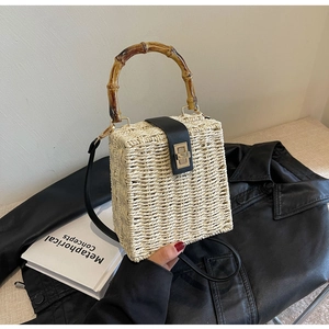 Detail of woven straw handbag with bamboo top handle and gold metal twist lock buckle
