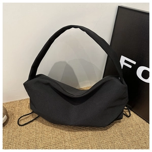Detail of a black nylon hobo bag with drawstring accents and wide shoulder strap