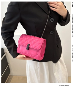Close-up of hot pink quilted chain bag with matte black clasp worn by a model