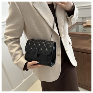 Classic black quilted crossbody bag with matte chain strap styled on a white blazer