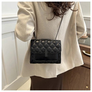 Detailed side view of black quilted crossbody bag with chain strap on a model