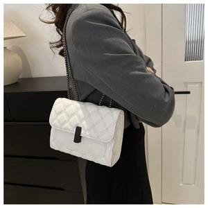 Classic white quilted crossbody bag with black lock buckle worn by a model in interior