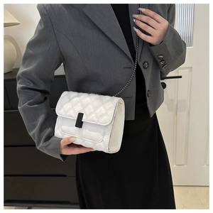 White quilted crossbody bag with diamond stitching and metal chain strap on female model