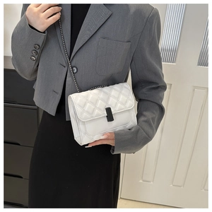 Close-up of white quilted chain bag on model showing elegant crossbody styling