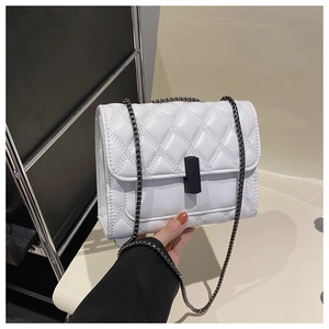 Detailed view of white quilted crossbody bag with black chain strap and metal clasp