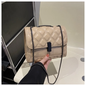 Detail of beige quilted flap bag with dark metal chain and rectangular black lock closure