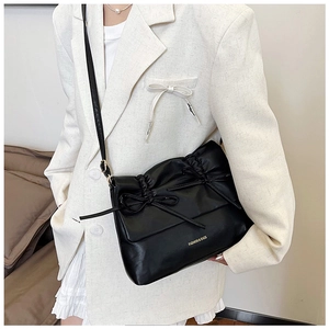 Dettaglio della borsa tote in PU nero con ruches e fiocchi su un blazer bianco