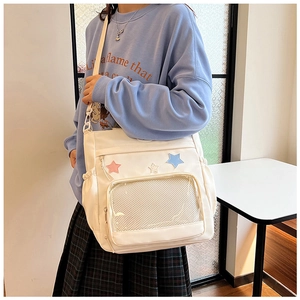 Dettaglio di borsa in tela bianca con toppe a stella colorate e tasca a rete con zip