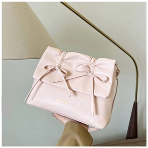 Dettaglio della borsa in pelle PU rosa con pieghe delicate e due fiocchi decorativi fini