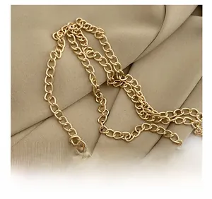 Macro detail of golden metal chain strap on textured tweed crossbody bag with woven fabric