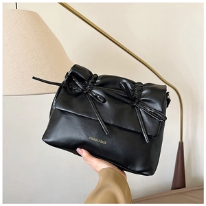 Dettaglio della borsa tote nera in ecopelle plissettata con eleganti fiocchi e scritta