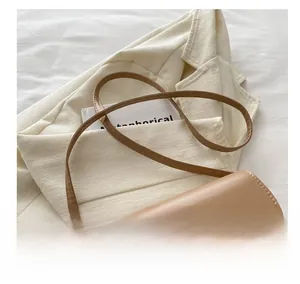 Detail of khaki leather saddle bag showing engraved logo and golden metal buckle on strap