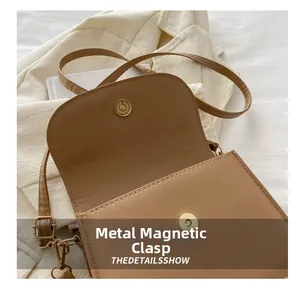 Detail of tan crossbody bag featuring golden magnetic snap closure and adjustable strap