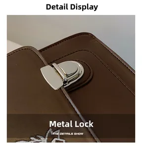 Detail of silver hardware lock and white floral embroidery on a brown leather JK messenger bag