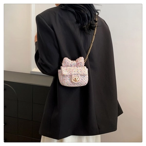 Detail of pink tweed shoulder bag with bow and gold chain on model's side