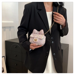 Detail of pink tweed crossbody bag with bow accent and gold chain strap on blazer