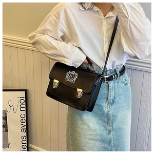 Close-up of black British style satchel bag featuring an embroidered academic crest and metal buckles