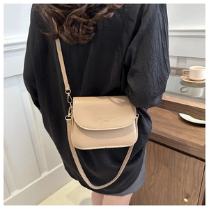 Détail du sac bandoulière beige clair avec logo embossé et finitions dorées chic