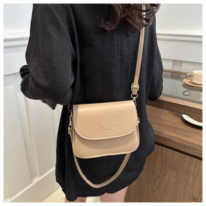 Close-up of minimalist beige saddle bag with adjustable strap worn on casual black top