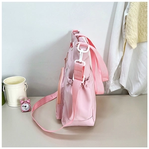 Dettaglio della borsa in tela rosa con tasca laterale e fibbia in plastica bianca