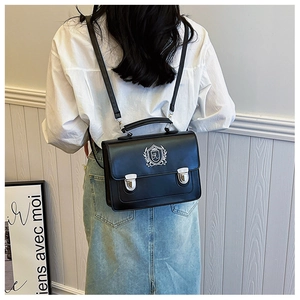 Detail of black British style satchel with white shield crest and silver metal buckles