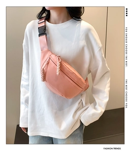 Pink nylon crossbody bag detail showing adjustable strap, plastic buckle and woven zipper pull