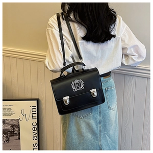 Detail of a vintage British-style satchel with silver shield embroidery and metal buckles