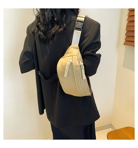 Detail of khaki nylon chest bag showing double zippers and adjustable buckle strap
