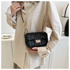 Detail of black quilted saddle bag with gold chain strap and metal ball adjustment