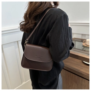 Detail of coffee brown square crossbody bag with embossed lettering and fine stitching