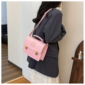 Detailed back view of pink British style satchel bag featuring embossed shield and gold buckles