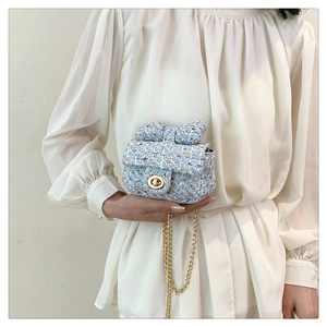 Blue tweed mini crossbody bag with a bow and gold chain strap shown on a model