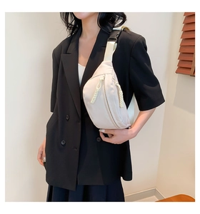 Dettaglio del marsupio in nylon bianco crema con doppia cerniera indossato da una modella