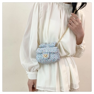 Detail of blue tweed mini crossbody bag with golden chain and cute bow decoration