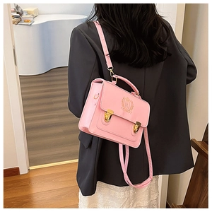 Detail showing pink faux leather satchel with golden emblem and adjustable shoulder strap