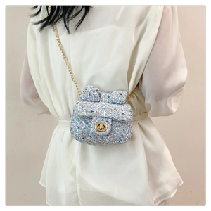 Close-up of light blue tweed mini crossbody bag with bow detail and gold chain strap