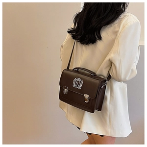 Detail of vintage brown satchel bag with crest embroidery and metal buckle closure