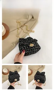 Close-up of black tweed mini bag with gold chain strap and metal turn-lock closure
