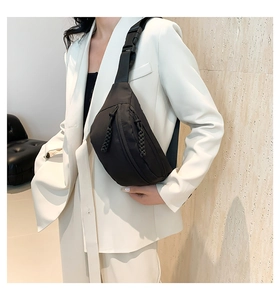 Detail of adjustable nylon strap and quick-release plastic buckle on black chest bag