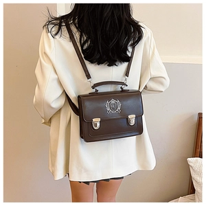 Detail of dark brown retro satchel featuring silver shield emblem and metallic buckle