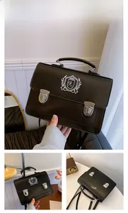 Detail of black British style satchel featuring white embroidered shield crest and silver buckles