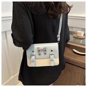 Close-up of color-block satchel bag with silver bow buckle and adjustable strap