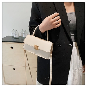 Nahaufnahme cremefarbene Mini-Vierecktasche mit goldenem Druckschloss und Tragegriff