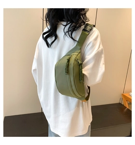 Olive green nylon crossbody bag detail showing woven zipper pulls and quick-release buckle