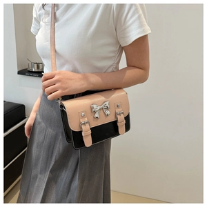 Detailed view of pink and black bow satchel bag worn by model for size reference