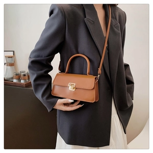Detailansicht der karamellbraunen Ledertasche mit Goldschnalle und Handgriff für Damen