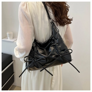 Close-up of black PU leather shoulder bag with chic bow accents and metal chain detail